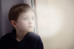 мальчик одиноко смотрит в окно идет дождь